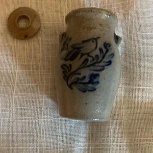 Puede incluir: Un pequeño jarrón de gres con un diseño de pájaro y flores en azul. El jarrón tiene dos asas pequeñas y una tapa a juego. El jarrón mide aproximadamente 7,6 cm de alto.