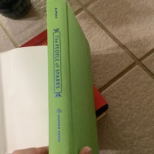 Puede incluir: Lomo de libro verde con el t&iacute;tulo "The People of Sparks" en texto blanco. El nombre de la editorial, Random House, est&aacute; impreso en la parte inferior. El libro est&aacute; parcialmente abierto, revelando p&aacute;ginas blancas.