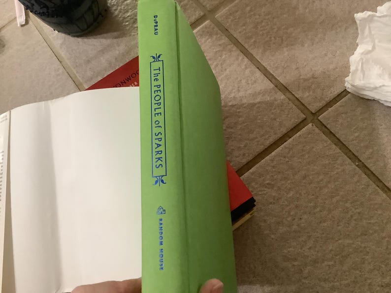 Puede incluir: Lomo de libro verde con el t&iacute;tulo "The People of Sparks" en texto blanco. El nombre de la editorial, Random House, est&aacute; impreso en la parte inferior. El libro est&aacute; parcialmente abierto, revelando p&aacute;ginas blancas.