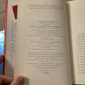 Puede incluir: Libro abierto con texto en las p&aacute;ginas. La p&aacute;gina izquierda tiene un resumen del libro, y la p&aacute;gina derecha tiene una tabla de contenido. El libro se titula "The Prophet of Yonwood" de Jeanne DuPrau.