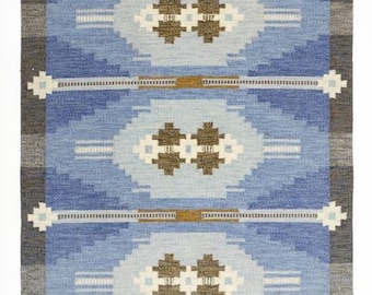 May include: A rectangular blue rug with a geometric pattern. The rug features a central design of repeating diamond shapes in shades of blue, brown, and white. The edges are bordered with gray and white accents, and the rug has a fringed edge.