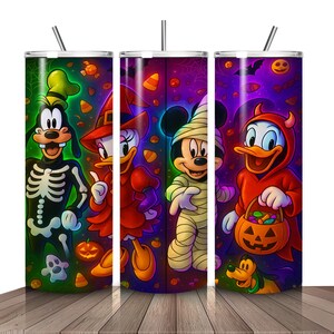 May include: Three Halloween-themed tumblers featuring Disney characters. Goofy in a skeleton costume, Daisy Duck as a witch, Mickey Mouse as a mummy, and Donald Duck as a devil. Each tumbler has a straw and a colorful Halloween background.