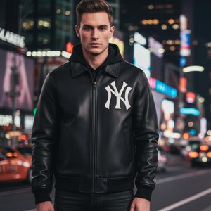 Könnte beinhalten: Schwarze Lederjacke mit weißem New York Yankees-Logo auf der Brust. Die Jacke hat einen Kragen, einen Reißverschluss und schwarze gerippte Bündchen und Saum. Der Hintergrund zeigt eine Stadt bei Nacht.