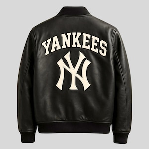 Op de afbeelding: Zwarte leren bomberjack met het woord "Yankees" in witte letters op de rug, boven een wit "NY"-logo. De jas heeft een zwarte geribbelde kraag, manchetten en zoom.