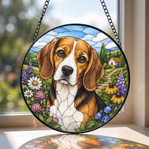 Peut inclure: Un attrape-soleil circulaire en vitrail représentant un chien beagle au pelage marron, noir et blanc. L'arrière-plan montre un paysage avec une petite maison, un chemin en pierre et des fleurs colorées dont des marguerites et des lupins.