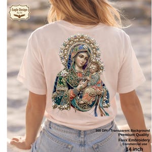 May include: A light pink t-shirt featuring a detailed illustration of a religious figure holding a child, adorned with pearls and intricate details. The image includes text indicating it's faux embroidery, 14 inches in size, and suitable for commercial use.
