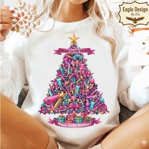 May include: White sweatshirt featuring a Christmas tree design composed of salon tools, bows, and gifts. The design includes the text "Hair Glam Yule" and "Happy Salon Holidays!" A gold star tops the tree.