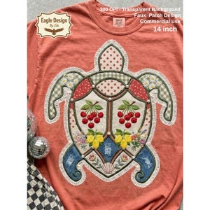 May include: Coral t-shirt with a turtle-shaped patch design. The patch features cherries, lemons, and floral elements, with a 35.5 cm diameter. The design incorporates various patterns and lace trim, with text that reads "Eagle Design By Eda".