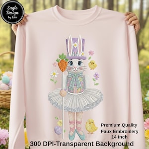 Puede incluir: Sudadera rosa claro con un diseño bordado de un conejito con tutú, sosteniendo una zanahoria. El conejito lleva un sombrero de copa morado y está rodeado de flores y pollitos. El texto "Premium Quality Faux Embroidery 35.56 cm" es visible.
