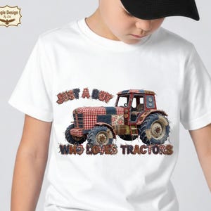 May include: White t-shirt with a tractor graphic. The tractor design incorporates patchwork patterns and floral accents. The text on the shirt reads "JUST A BOY WHO LOVES TRACTORS". A unique and eye-catching design.