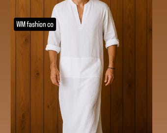 May include: A white linen tunic with a V-neck and long sleeves, rolled up at the elbows. The tunic has a front pocket and is floor-length. The text "WM fashion co" is visible in the image.
