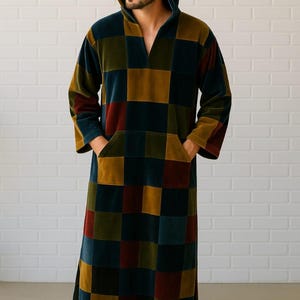 Puede incluir: Una bata larga con capucha y un estampado de tablero de ajedrez en tonos azules, dorados y rojos. La bata tiene un bolsillo delantero y mangas largas. El modelo lleva la bata. La bata est&aacute; hecha de un material suave y aterciopelado.