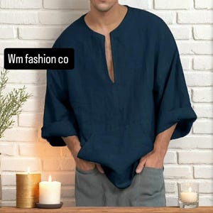 Op de afbeelding: Een marineblauw linnen shirt met een V-hals en driekwart mouwen. Het shirt heeft een relaxte pasvorm en toont de tekst "Wm fashion co" in een zwart kader.