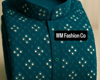 Op de afbeelding: Teal overhemd met een opstaande kraag en gedetailleerde borduursels. Het overhemd heeft een knoopsluiting en kleine, reflecterende versieringen. De tekst "WM Fashion Co" staat op de voorkant.