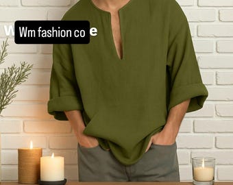 May include: Olive green long-sleeve shirt with a V-neck collar and rolled-up sleeves. The shirt is made of a soft, flowing fabric. The text "Wm fashion co e" is visible in the image. The shirt is paired with gray pants.