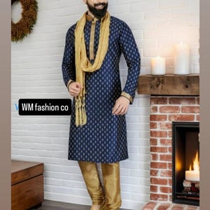May include: A navy blue kurta pajama set with a gold scarf. The kurta features a subtle diamond pattern and gold trim. The matching pants are gold. The outfit is worn with gold shoes. The text "WM fashion co" is visible.