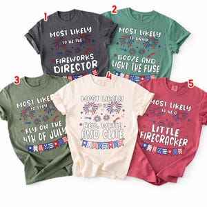 May include: Five t-shirts in various colors, each with a unique patriotic-themed graphic. The shirts feature phrases like "Most Likely to be the Fireworks Director" and "Red, White, and Cute," with firework and flag illustrations.