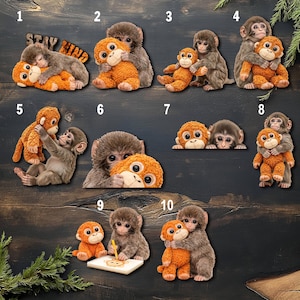 May include: A collection of monkey-themed plush toys and figurines. The toys are in various poses, including hugging, cuddling, and playing. The color palette includes shades of brown and orange, with some items featuring the text "Stay Kind".