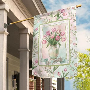 May include: A decorative garden flag featuring a watercolor design of pink tulips in a vase. The flag has a light green and pink floral border and a banner with the text "The Smiths". The flag is hanging on a porch.