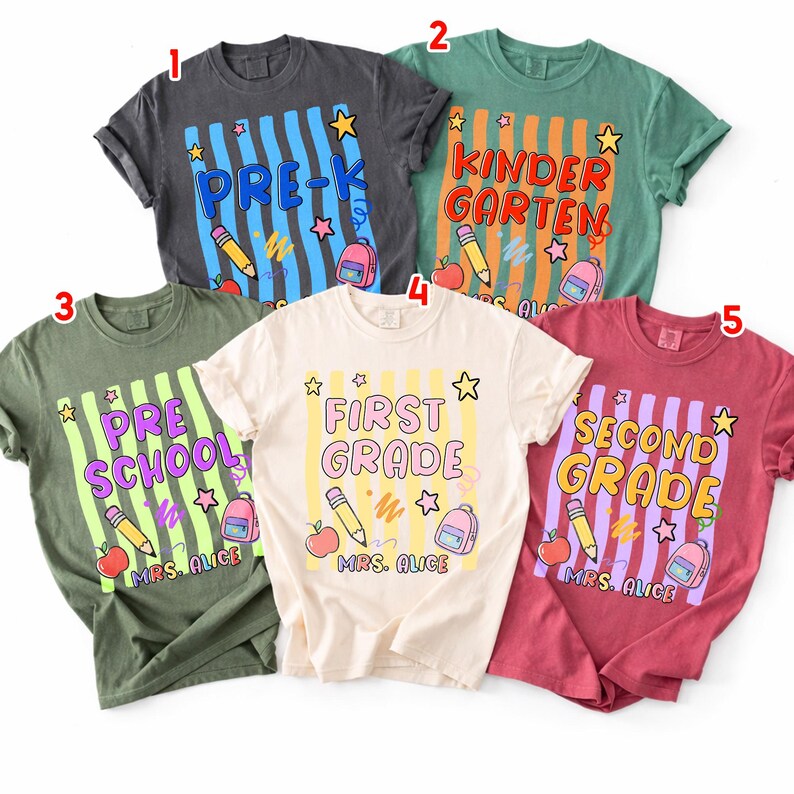 以下が含まれることがあります： 学校をテーマにしたデザインの半袖Tシャツ5枚。各シャツには、「Pre-K」や「First Grade」などの学年が表示され、鉛筆、リンゴ、バックパックなどの学用品が描かれています。シャツの色は、グレー、グリーン、レッドなど様々です。