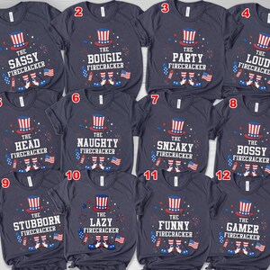 May include: Navy blue t-shirts with various phrases and graphics related to fireworks and the Fourth of July. Each shirt features a top hat, fireworks, and American flags. Phrases include "The Sassy Firecracker," "The Bougie Firecracker," and "The Party Firecracker."