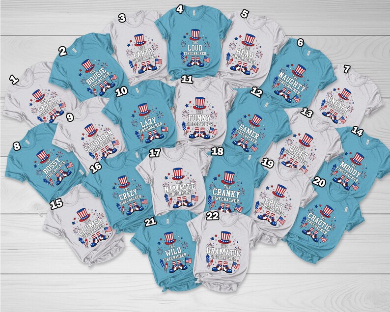 May include: A collection of baby and toddler t-shirts in various colors, each featuring a patriotic firecracker design with text. The shirts have short sleeves and are suitable for Independence Day celebrations.