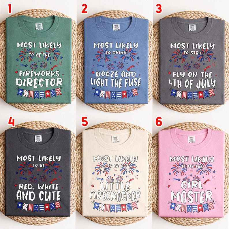 May include: Six different-colored t-shirts with text related to the 4th of July. The shirts are green, blue, gray, dark gray, beige, and pink. Each shirt has a different phrase, such as "Fireworks Director" or "Little Firecracker", with fireworks and banner graphics.