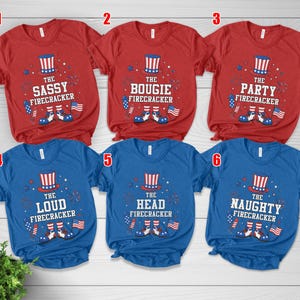 May include: Red and blue t-shirts with patriotic designs. Each shirt features a firecracker graphic with text: "The Sassy Firecracker," "The Bougie Firecracker," "The Party Firecracker," "The Loud Firecracker," "The Head Firecracker," and "The Naughty Firecracker."
