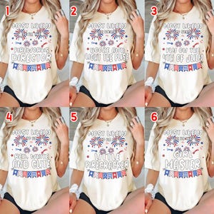 May include: A collection of six cream-colored t-shirts, each with a unique patriotic design. The shirts feature phrases like "Fireworks Director," "Booze and Light the Fuse," and "Fly on the 4th of July," in red, white, and blue.