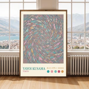Puede incluir: Un póster enmarcado con un diseño abstracto en espiral colorido, con tonos de azul, rosa y amarillo. Incluye el texto "YAYOI KUSAMA TOKYO" y texto japonés. La obra de arte se exhibe en una habitación con una ventana.