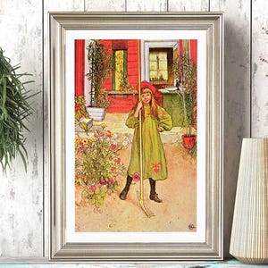 Op de afbeelding: Een ingelijste vintage prent toont een jong persoon in een groene jurk en rode hoed met een hark in een tuin. Het kunstwerk zit in een zilveren lijst, tegen een witte houten wand. Een vaas en een zwart-wit gestippelde beker staan op een blauwe plank.