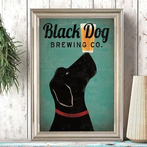 Puede incluir: Lámina enmarcada con un perro negro equilibrando un vaso de cerveza en la nariz. El texto "Black Dog Brewing Co." está encima. El fondo es turquesa y el marco es plateado.