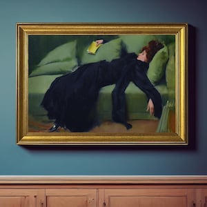 以下が含まれることがあります： 額縁に入った絵画は、黒いドレスを着た女性が緑色のソファに横たわっている様子を描いています。このアートワークは金色のフレームで、木製のキャビネットの上にある青い壁に飾られています。女性は黄色の本を持っています。