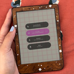 May include: A wooden-framed tablet with a screen displaying app icons. The screen shows options for "Do Not Disturb", "On a date with my best friend", "Personal", and "Work". The frame is decorated with small white flower and gem accents.