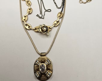 May include: A gold layered necklace with a rose charm and a pendant featuring a large clear crystal. The necklace includes a black chain and a gold chain.