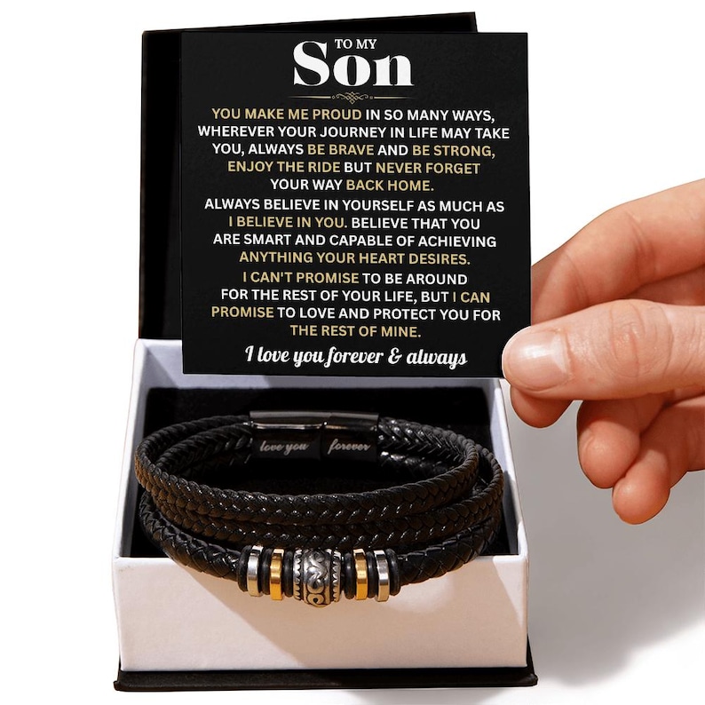 May include: Black leather bracelet with silver and gold accents, presented in a gift box. The bracelet features a braided design and a magnetic clasp. The gift box includes a card with a heartfelt message to a son.
