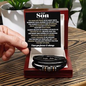 May include: A black braided leather bracelet with silver and gold accents, presented in a red wooden box. The box contains a card with the text "TO MY SON" and a heartfelt message. The bracelet is inscribed with "love you forever".