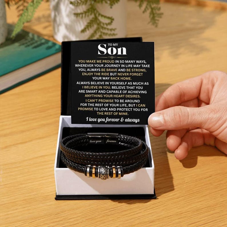 May include: A black leather bracelet set with silver and gold accents, presented in a gift box. The box includes a card with the text "To My Son" and a heartfelt message. The bracelet is a thoughtful gift.