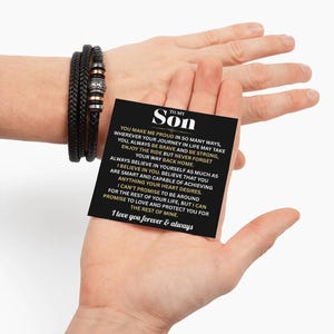 May include: Black braided leather bracelet with silver and copper-colored beads. A black card held in a hand reads "TO MY Son" with a loving message. The bracelet is a thoughtful gift.