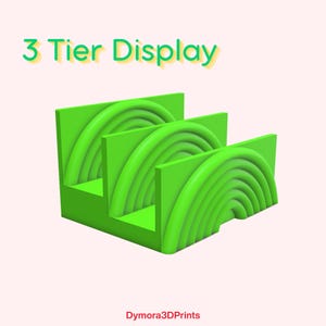 K&ouml;nnte beinhalten: Ein leuchtend gr&uuml;ner 3-st&ouml;ckiger Pr&auml;sentationsst&auml;nder mit einem abgestuften Design. Jede Ebene weist eine Reihe von gebogenen, halbkreisf&ouml;rmigen Rillen auf. Der Text "3 Tier Display" steht oben. Der untere Teil des Bildes tr&auml;gt den Text "Dymora3DPrints".