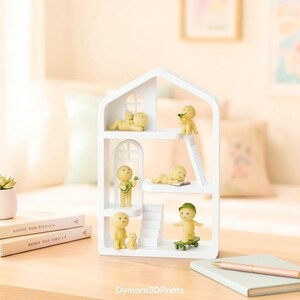 May include: A white, multi-tiered shelf unit shaped like a house, populated with small yellow figures. One figure plays a guitar, another reads, and one rides a skateboard. The shelf sits on a wooden surface with books and a notebook.
