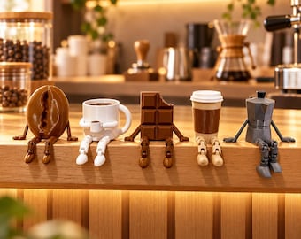May include: A set of five small figurines sitting on a wooden edge, including a brown coffee bean, a white mug with a tiny cup, a brown chocolate bar, a tan paper coffee cup, and a grey metal stovetop espresso maker, all with articulated limbs.