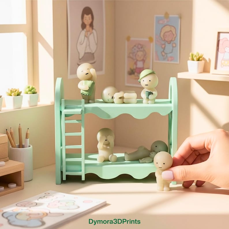 Op de afbeelding: Een mintgroen stapelbed met verschillende kleine, lichtgekleurde beeldjes. Sommige beeldjes staan, andere liggen. De sc&egrave;ne speelt zich af in een kamer met kunstwerken en kleine potplanten. De tekst "Dymora3DPrints" is zichtbaar.