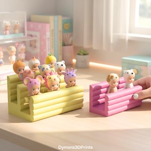 Peut inclure: Une collection de petites figurines, chacune portant un chapeau sur le thème des animaux, exposées sur des présentoirs jaunes et roses à plusieurs niveaux. Les figurines sont disposées sur un bureau en bois, avec une fenêtre et d'autres objets décoratifs en arrière-plan.