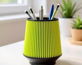 May include: A lime green and black desk organizer holding pens and pencils. The organizer has a ribbed design and a flared shape. Several pens and pencils of various colors are visible inside the organizer.