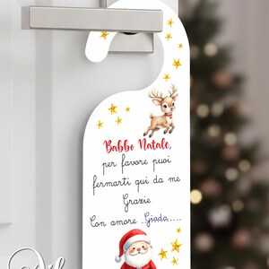 Può includere: Appendiabiti bianco a tema natalizio. Il design include una renna, Babbo Natale e stelle dorate. Il testo in italiano recita: "Babbo Natale, per favore puoi fermarti qui da me Grazie Con amore Giada..."