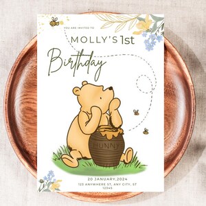 May include: A birthday invitation featuring a cartoon bear with a honey pot. The invitation reads "Molly's 1st Birthday" with the date and address below. The design includes bees, flowers, and a dotted line.