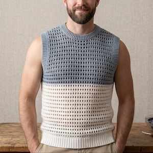 May include: A sleeveless, two-tone crochet vest. The top portion is a light blue, and the bottom is off-white. The vest has a round neckline and a textured, open-weave design. The garment is worn by a person.