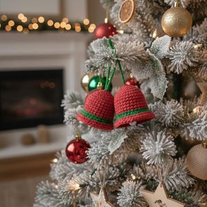 May include: Two red crocheted bell ornaments with green and white trim hang on a flocked Christmas tree. The tree is decorated with various ornaments, including gold and red baubles, and wooden star-shaped decorations. The background features a fireplace and soft lighting.