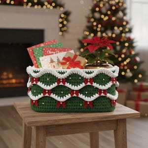 May include: A handcrafted green crochet basket with white scalloped trim, red bows, and pearl accents. The basket holds Christmas cards, a small wrapped gift, and a poinsettia plant. The basket is on a wooden table, with a Christmas tree in the background.